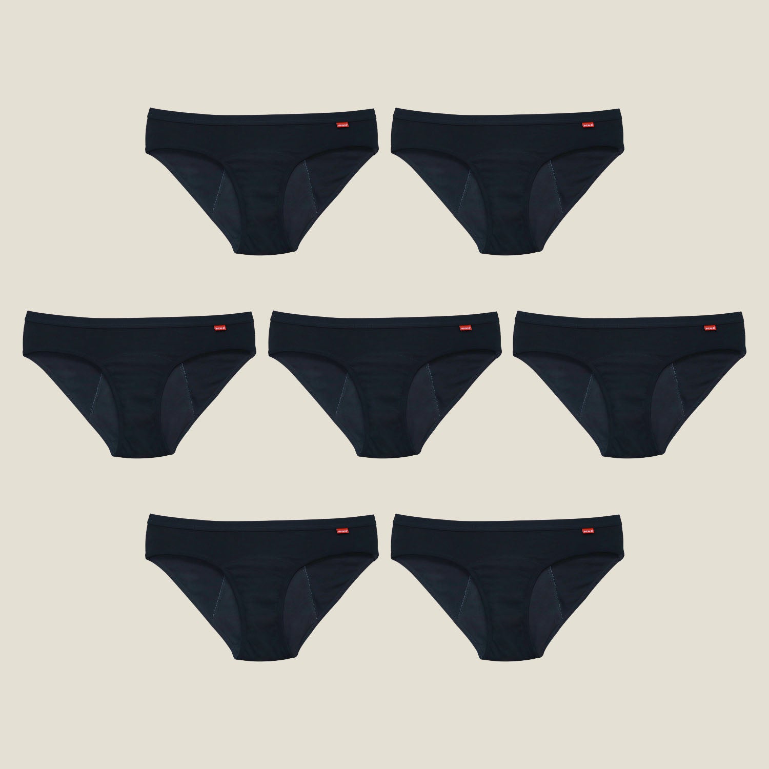 Flat lay of 7 black WUKA Basics™ Hipster period pants for medium flow arranged in rows on a beige background.