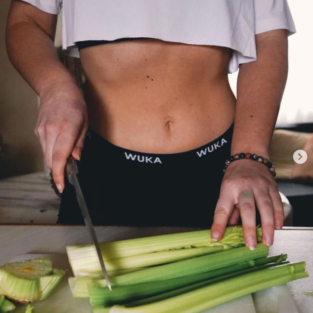 woman wearing WUKA Ultimate Boxer Shorts in the kitchen, chopping celery 