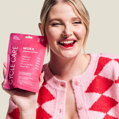 Smiling woman holding WUKA Hormone Support Gummies with strawberry flavour for hormone balance and PMS support.